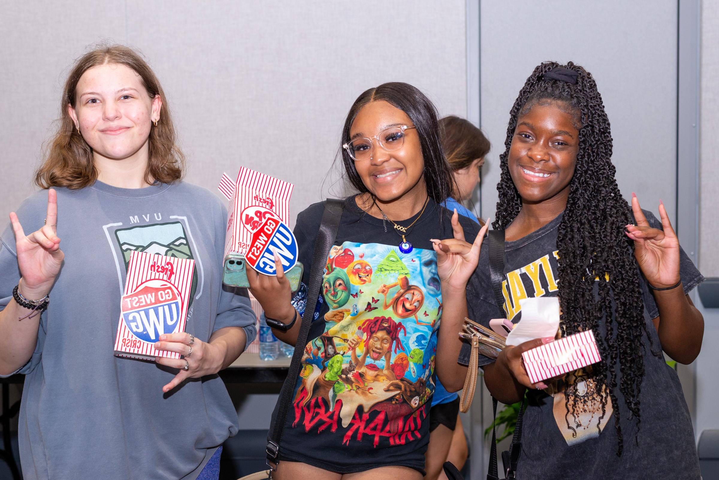 Students at Screen on the Green holding popcorn, 在线博彩 shield swag, and holding up the wolf hand sign